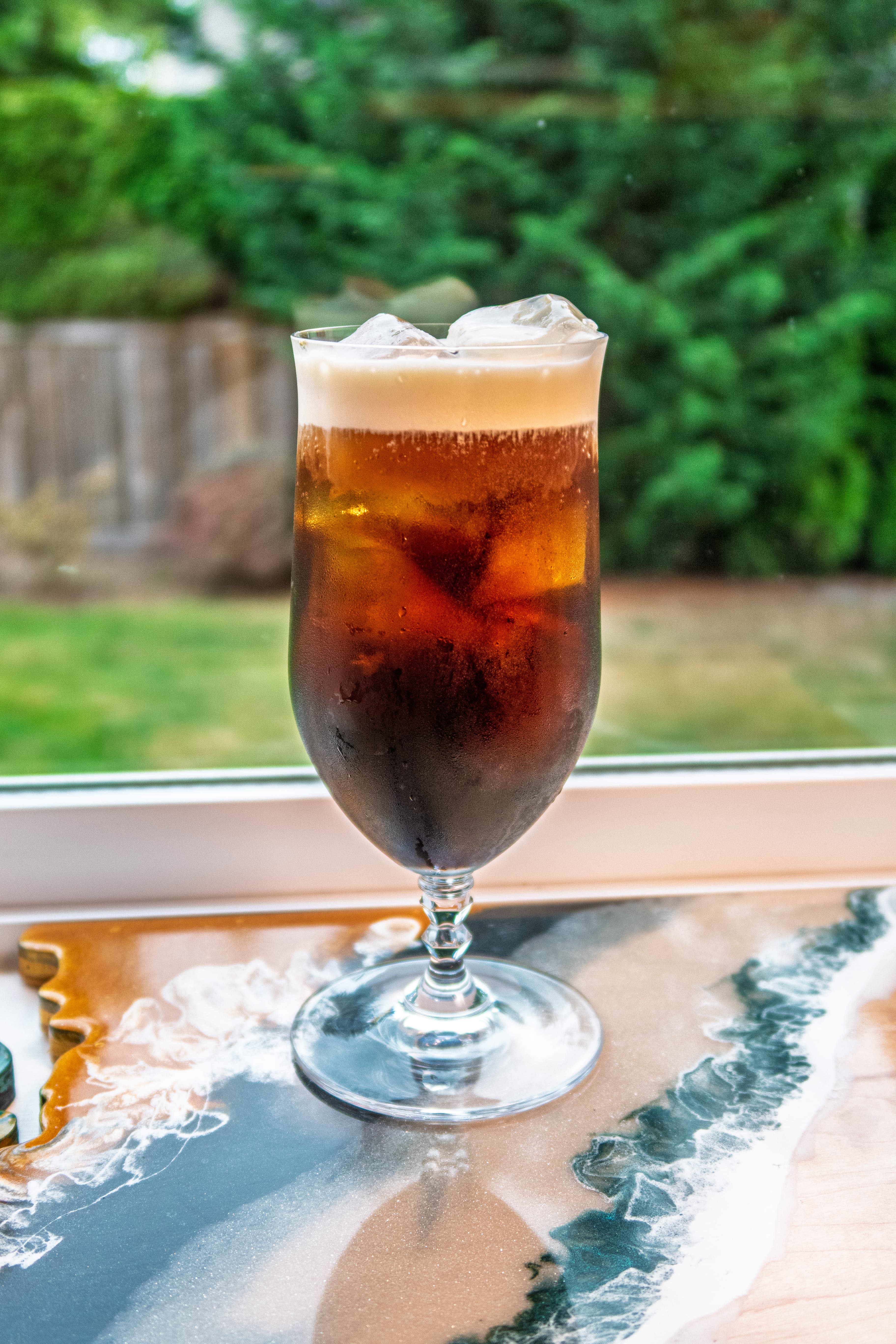 A layered cocktail with a delicate float, lit warmly